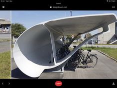 two bicycles are parked in front of a large white structure on the side of a road