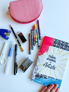 the contents of a travel journal laid out on a table with pens, pencils and markers