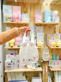 a person holding a white bag in front of shelves filled with toys and other items