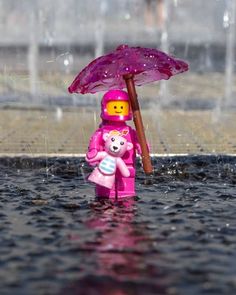 a pink lego bear holding an umbrella in the rain