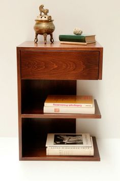 a wooden shelf with two books and a vase on top, sitting next to each other