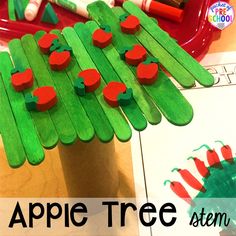 an apple tree made out of popsicle sticks on a table with crayons