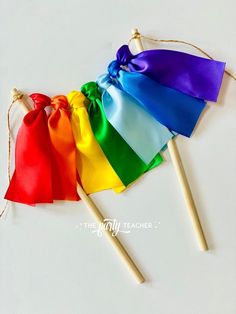 three rainbow colored flags with wooden sticks tied to them