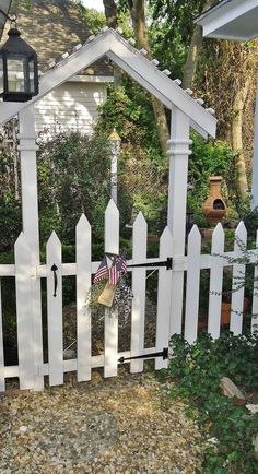 a white picket fence with an american flag on it and a lantern hanging from the top