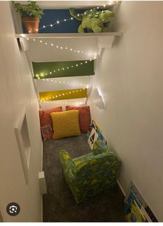 a small room with a couch and some plants on the shelves above it is decorated with lights