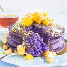 a blue plate topped with purple pancakes covered in toppings