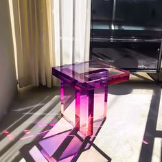 a glass table sitting in front of a window with the sun shining through it and casting long shadows on the floor