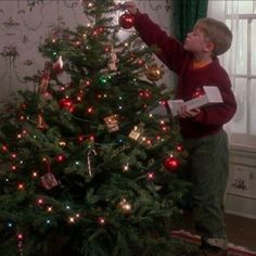 a young boy decorating a christmas tree