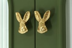 two golden rabbit head hooks on a green cabinet