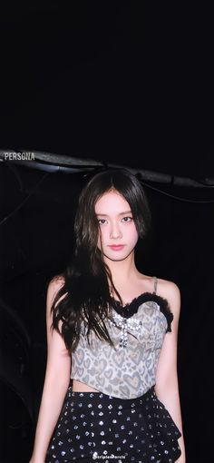 a young woman posing for a photo in front of a black background wearing a leopard print top