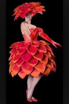 a woman in an orange and red dress with large feathers on it's head