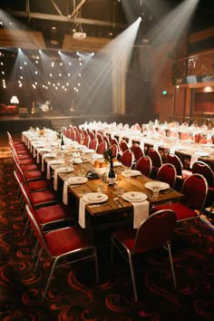 a banquet hall with long tables and red chairs