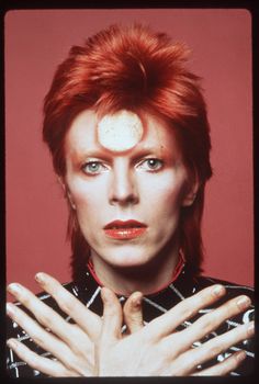 a man with red hair and piercings holding his hands up in front of him