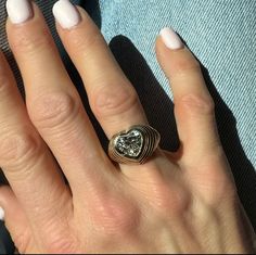 a woman's hand with two rings and a heart shaped diamond on top of it