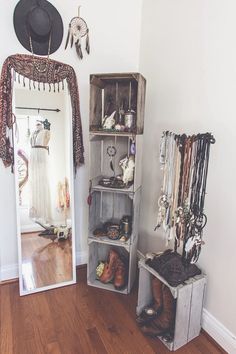 a mirror sitting on top of a wooden floor next to a shelf filled with jewelry