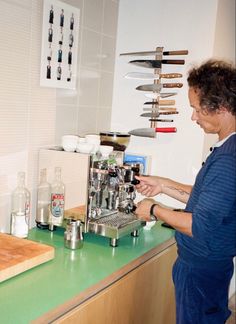 a man standing in front of a green counter top next to a wooden cutting board