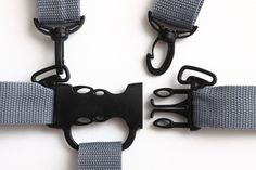 three black buckles are attached to two gray webbnnails on a white surface