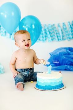 a baby boy sitting in front of a birthday cake