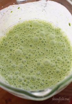 a blender filled with green liquid on top of a wooden table