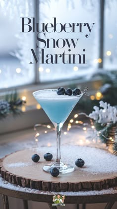 a blueberry snow martini sitting on top of a table next to a christmas tree