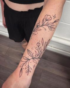 a woman's arm with flowers and leaves on the left side of her body