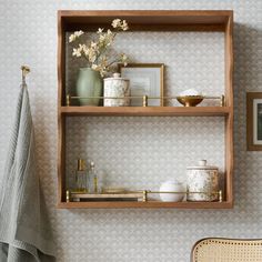 two wooden shelves with pictures and vases on them next to a wall mounted towel rack