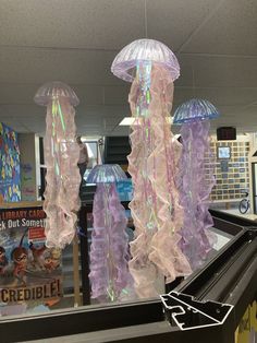 some jellyfish are hanging from the ceiling in front of a store window with plastic coverings