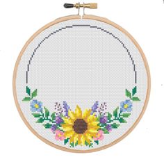 a cross stitch sunflower with leaves and flowers in the hoop on a white background