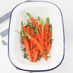 carrots are in a white bowl on a blue and white towel