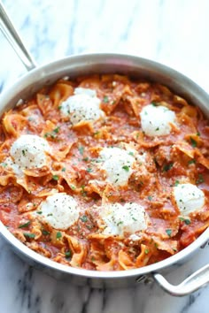 a pan filled with pasta and cheese on top of a marble counter