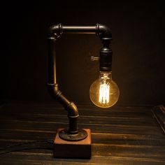 a light bulb sitting on top of a wooden table next to a pipe and lamp