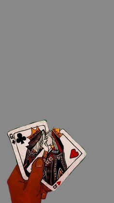 a hand holding two playing cards in front of a gray background with the king and queen of spades