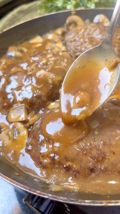 a spoon is being used to stir food in a pan with mushrooms and gravy