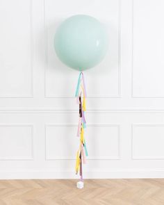 a green balloon with streamers hanging from it's side on a wooden floor