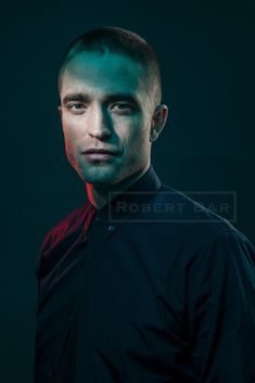 a man in a black shirt is looking at the camera with green light on his face