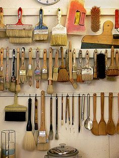 there are many different brushes and brooms hanging on the wall