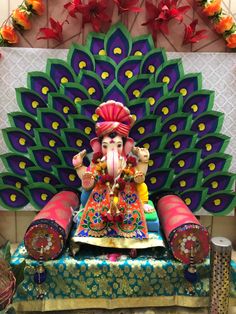 an elephant statue sitting on top of a table next to a large peacock feather decoration