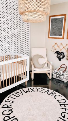 a baby's room with a white crib, chair and black and white rug