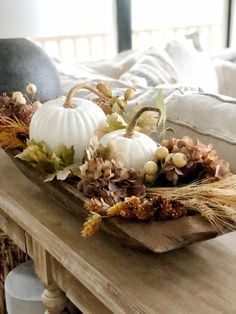 a wooden table topped with white pumpkins and dried flowers on top of it's sides