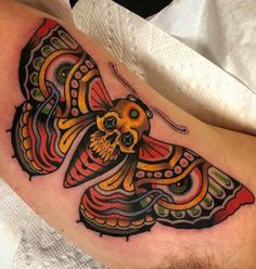 a colorful butterfly tattoo on the arm and leg, with a skull in it's center