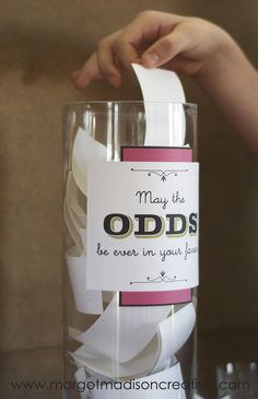 a person is holding a glass with some paper on it that says, may the odds be ever in your place