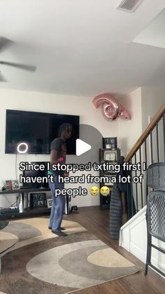 a person standing in a living room next to a stair case and a flat screen tv