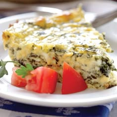 a slice of quiche on a plate with tomatoes