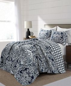 a bed with blue and white comforters in a bedroom next to a night stand