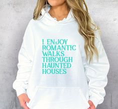 a woman wearing a white hoodie that says i enjoy romantic walks through haunted houses