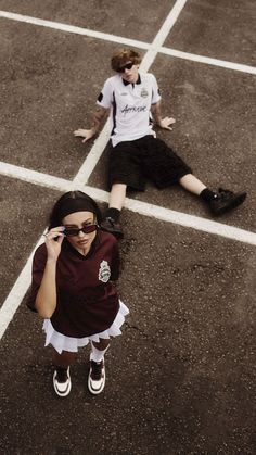 two people laying on the ground with one talking on a cell phone