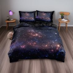 a bed covered in a black and purple galaxy comforter next to two night stands