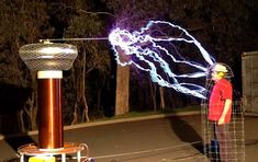 a man standing in front of a large metal object with electrical wires coming out of it