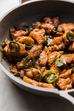 a pan filled with chicken and peppers on top of a table