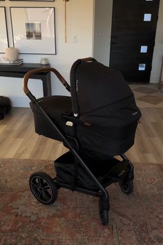 a black stroller sitting on top of a wooden floor